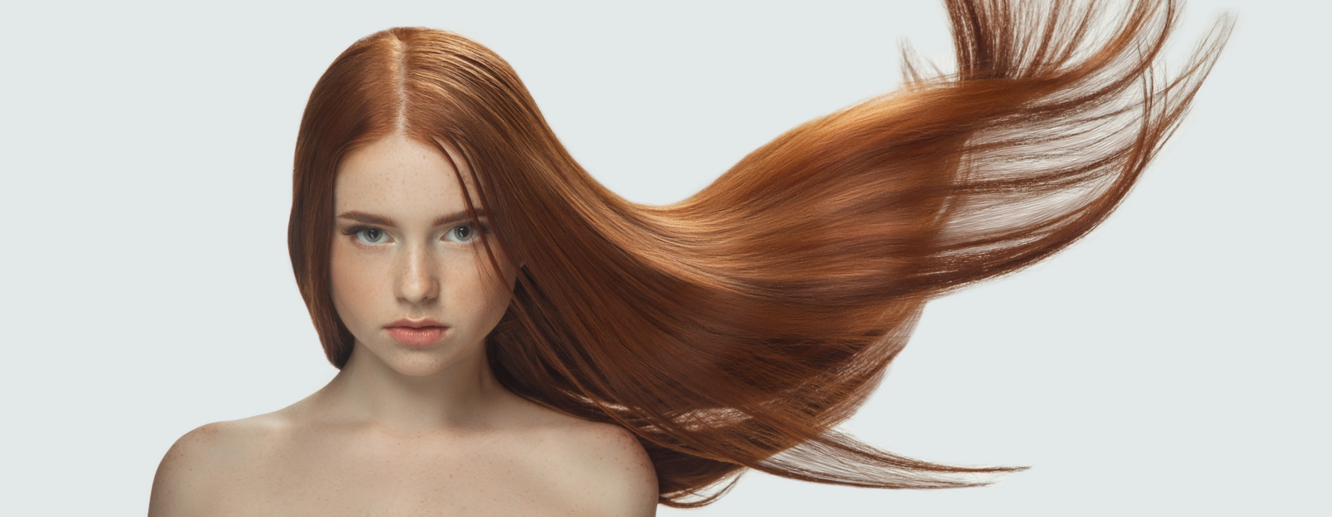 A woman with long red hair is looking at the camera.